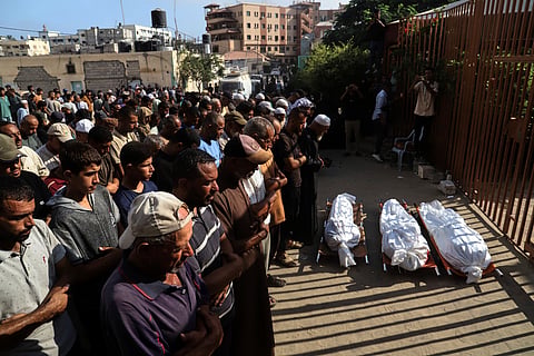 Mourners pray over the bodies of three Palestinians, killed along with others in Israeli strikes, during their funeral outside Nasser Hospital in Khan Younis, southern Gaza Strip, Saturday, Aug. 23, 2025. 