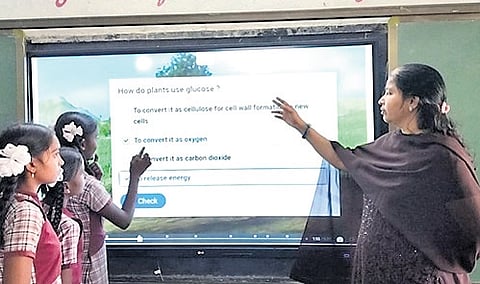 Maram Pavithra points to a question at the digital board as students look on during a class at the Zilla Parishad High School (ZPHS), Penpahad 