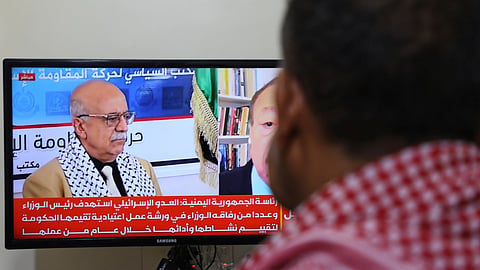 A man watches the news on TV, displaying footage of Ahmed al-Rahawi, the prime minister of the Houthi-controlled government, who was killed, along with others, in Thursday's Israeli strikes on the capital, in Sanaa, Yemen, Saturday, Aug. 30, 2025