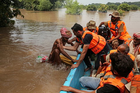 A rescuer pulls a flood-affected man on board a boat after the flood in the Chenab river, in Muzaffargarh in Punjab province on September 6, 2025. Water has gushed into the eastern province, Pakistan's breadbasket and home to about half of its 255 million people, with three transboundary rivers swelling beyond their banks. 