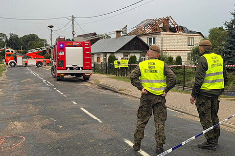 Firefighters and territorial defence officers stand close to the destroyed roof of a house, after Russian drones violated Polish airspace during an attack on Ukraine, in Wyryki near Lublin, Poland, Thursday, Sept. 11, 2025.