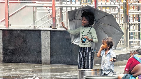 Kids take shelter under an umbrella during a drizzle on Mint Street in Chennai on Saturday.
