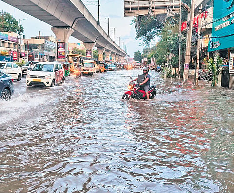A commuter struggles to maintain balance in the swirling water that inundated the main road near Rasoolpura Metro station in Hyderabad on Thursday. 