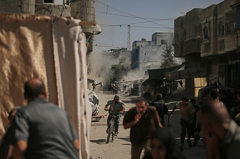 Palestinians run for cover during an Israeli military strike on a building in Gaza City, Saturday, Sept. 13, 2025.