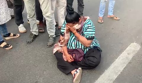 The woman sat down in the middle of the road, blocking vehicles and triggering curiosity among passers-by.
