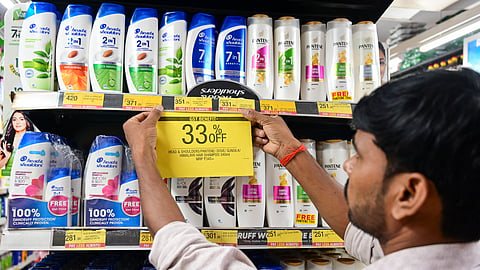  A man puts a 33% off poster on shampoo bottles, at a shop, in Prayagraj, Monday, Sept. 22, 2025. The new GST rates came into effect.