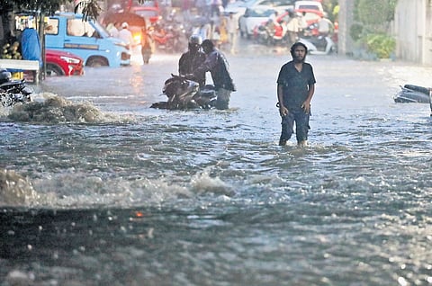 A youth wades through knee-deep water near Raj Bhavan Road.