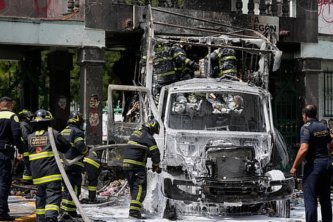 Firefighters extinguish a garbage truck that demonstrators set on fire  during a protest marking the 11th anniversary of the disappearance of 43 students from an Ayotzinapa rural teacher's college, outside the entrance of Campo Militar, in Mexico City, Thursday, Sept 25, 2025.