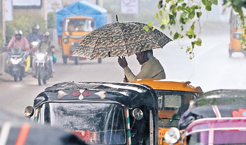 Man with umbrella rides a vegetable-laden auto on rainy road near ESI Hospital Metro, Hyderabad the Godavari river 