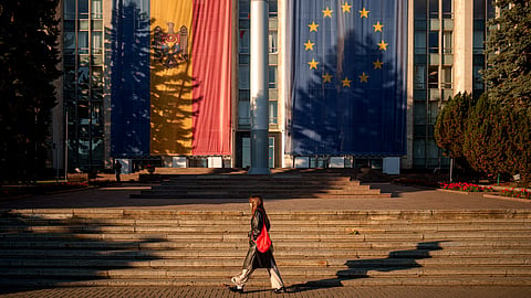 A woman walks in front of the government building, decorated with European Union and Moldovan flags, in Chisinau, Moldova, Friday, Sept. 26, 2025, ahead of parliamentary elections taking place on Sept. 28.