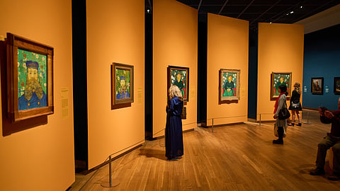 People look at portraits of the Roulin family, Jospeh, 2 paintings on the left, and his wife Augustine, 3 paintings on the right, brought together by the Van Gogh Museum in Amsterdam, Netherlands, Wednesday, Oct. 1, 2025. 