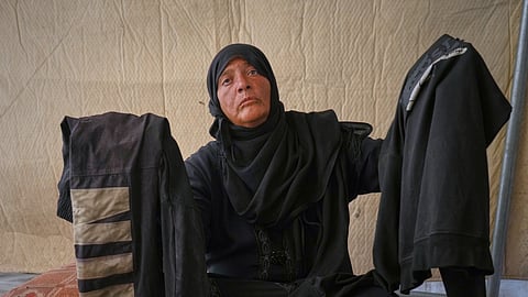 Fadwa al-Ghalban holds clothes belonging to her son, Mosaab, at her tent in Muwasi, along Gaza's southern coast, Oct. 3, 2025. Fadwa has had no word from Mosaab since July, when his cousins last saw him near their house as an Israeli strike destroyed it in the southern town of Maan.