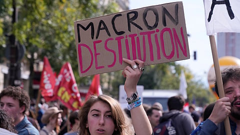 A demonstrator holds a poster reading "Macron, dismissal" during a new round of strikes and protests against the caretaker government and cost-cutting Thursday, Oct. 2, 2025, in Paris.