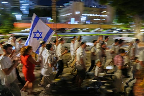 Jewish revelers dance and hold up the Torah as they celebrate the holiday of Simchat Torah next to the plaza known as hostages square, in Tel Aviv, Israel, Tuesday, Oct. 14, 2025. 