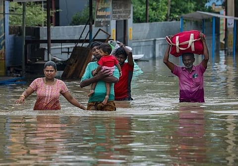 People shift from a flooded road after heavy rainfall, in Tirunelveli district, Tamil Nadu.