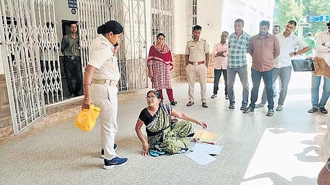 A policewoman taking away the bottle of kerosene from the woman 
