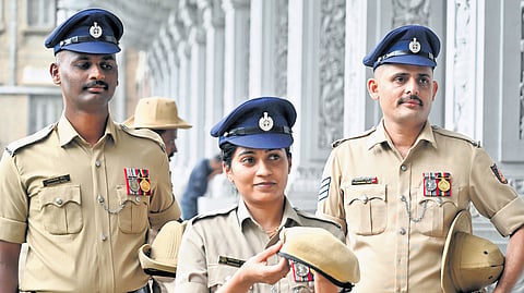 Police personnel wearing the new navy blue peak caps hold the old slouch hats 
in Vidhana Soudha in Bengaluru on Tuesday