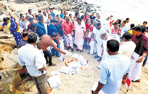 Residents of Munambam burn copies of their property document to protest the delay in restoration of their revenue rights.