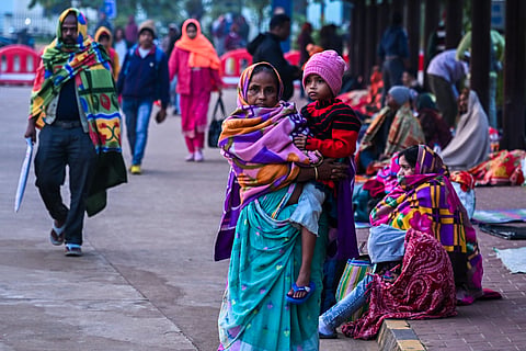 People wrap themselves with shawls and winter clothes to get rid of cold while waiting outside AIIMS as temperature dips in Bhubaneswar on Monday. 