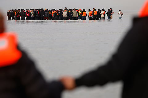 Migrants push a small boat in an attempt to reach Britain.