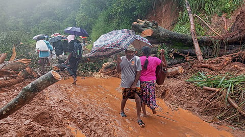 Landslide survivors cross a section of a road that is blocked by debris in Hanguranketha, Sri Lanka, Saturday, Nov. 29, 2025