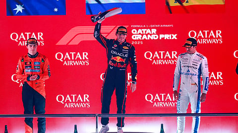 Race winner Red Bull Racing's Max Verstappen (C) celebrates with the trophy next to second placed McLaren's Oscar Piastri (L) and third placed Williams' Carlos Sainz at the end of the Formula One Qatar Grand Prix on November 30, 2025.