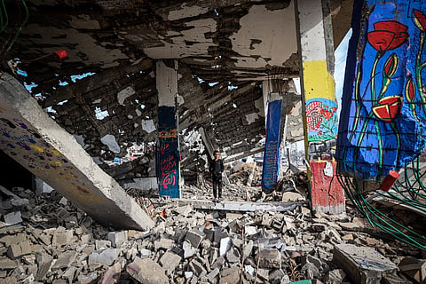 A boy stands amid murals painted on a destroyed building in the Maghazi refugee camp outside Deir al-Balah on December 8, 2025.