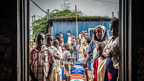 Refugees from eastern Democratic Republic of the Congo, newly arrived after renewed fighting broke out, line up with buckets at a food distribution point at Nyarushishi Transit Camp in Rusizi district on December 11, 2025.