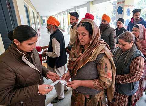 A police official checks documents of voters at a polling station during the zila parishad and panchayat samiti elections on the outskirts of Amritsar.