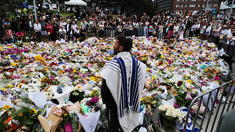 Rabbi Yossi Friedman speaks to people gathering at a flower memorial by the Bondi Pavilion at Bondi Beach on Tuesday following Sunday's shooting in Sydney
