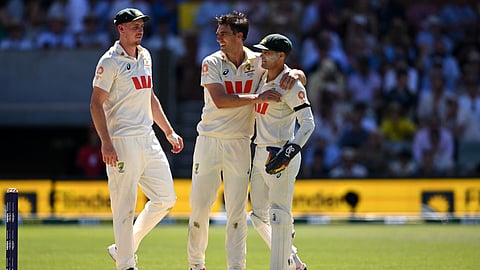 Australia's Pat Cummins (C) celebrates with teammates Alex Carey (R) and Cameron Green (L) after dismissing England batsman Jamie Smith on the second day of the third Ashes cricket Test match on December 18, 2025. 