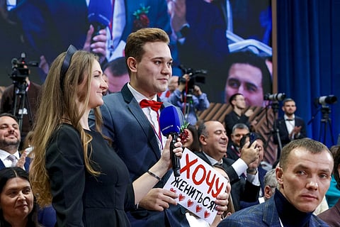 Kirill Bazhanov of Yekaterinburg’s Channel 4, center, asks a question, holding a sign he wanted to get married, during Russian President Vladimir Putin's  annual news conference at Gostinny Dvor in Moscow, on Friday, Dec 19, 2025.