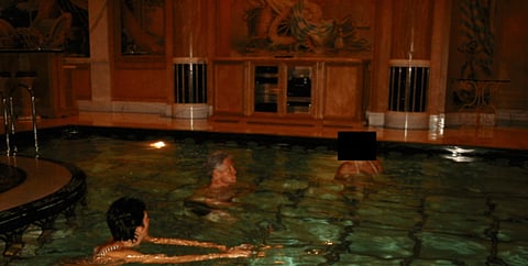 This undated, redacted photo released by the U.S. Department of Justice shows Ghislaine Maxwell and former President Bill Clinton swimming with an unknown person. 