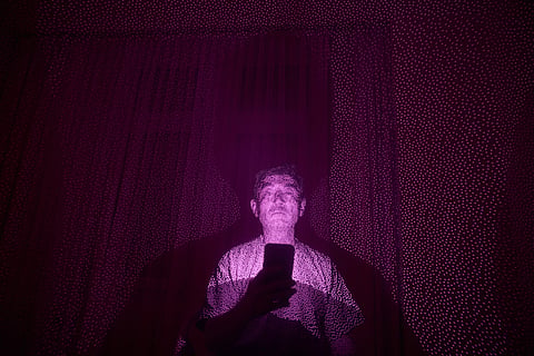 Former Xinjiang government engineer Nureli Abliz, who saw firsthand how surveillance technology flagged thousands of people in China for detention, even when they had committed no crime, is illuminated by cellphone infrared facial recognition beams as he sits for a photo in Mannheim, Germany, where he is currently living in exile, July 23, 2025. 