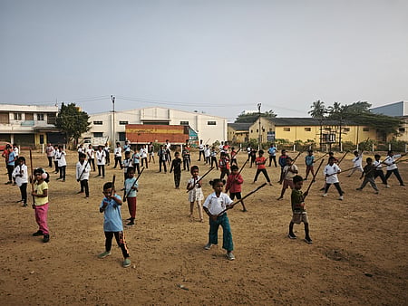 Young Silambam students, ranging from small children to teenagers, practice with bamboo sticks during an early morning training.