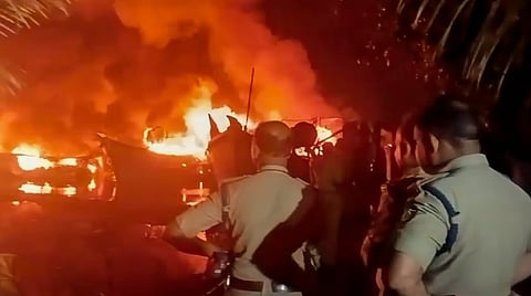 Police personnel at the site where fishing boats caught fire at Ashtamudi Lake 
