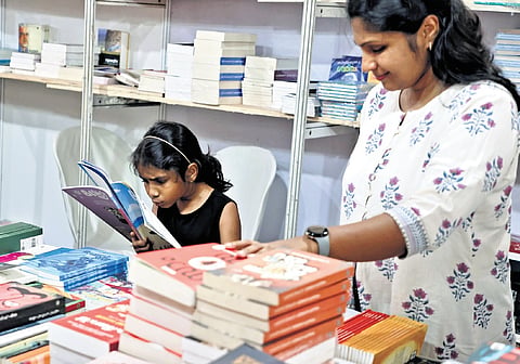 A young reader deeply engrossed in a book with her mother alongside at the Kerala Legislature International Book Festival, held on the assembly premises on 
Sunday 
