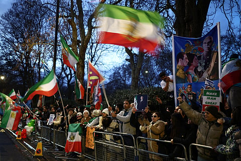 Anti-Iranian regime protesters wave Iranian flags during a gathering outside the Iranian Embassy, central London, on January 12, 2026. 