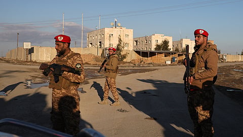 Syrian government forces stand guard outside Al-Aqtan prison on the outskirts of Raqqa, northeastern Syria, 