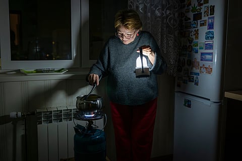 A woman cooks food on a gas burner by lantern light during a blackout in Kyiv following Russian attacks on energy infrastructure in Kyiv, Ukraine, Tuesday, Jan. 20, 2026. 
