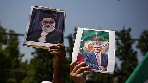 A protester holds a poster of Iran's exiled crown prince Reza Pahlavi, right, and defaced poster of Iran's Supreme Leader Ayatollah Ali Khamenei during a rally in support of anti-government protests in Iran, in Santiago, Chile, Tuesday, Jan. 20, 2026. 