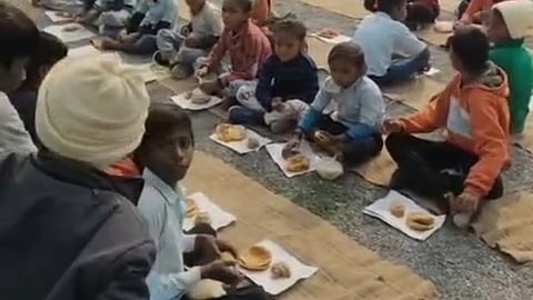 Students at the government school in Bhatigwan (Maihar) sit on the floor, eating their Republic Day mid-day meal served on ink-stained, torn notebook pages.