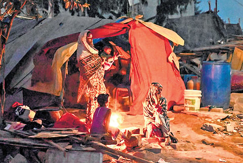 As temperature dips at night, residents of Kogilu keep warm around a bonfire after their houses were demolished during a recent GBA drive