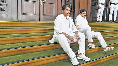 Leader of Opposition in Assembly R Ashoka and former home minister Araga Jnanendra sit on the steps leading to the Assembly after the Opposition’s overnight dharna seeking the resignation of Excise Minister RB Timmapur