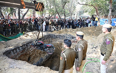 The bike of a motorcyclist who plunged into an uncovered pit dug for construction work by Delhi Jal Board, being lifted out, at Janakpuri, in New Delhi.