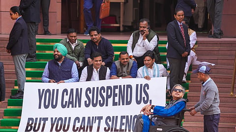 Congress MP Shashi Tharoor, front right, arrives in a wheelchair as Lok Sabha MPs who were suspended from the Lok Sabha on Tuesday protest outside the Parliament. 