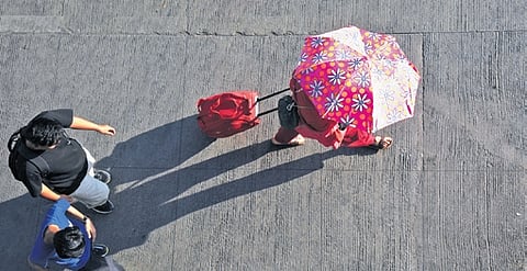 A passenger at Bengaluru’s Kempegowda Bus Terminal uses an umbrella to protect herself from the summer heat 