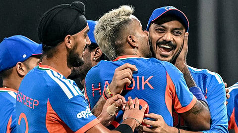 Axar Patel (R) being kissed by his teammate Hardik Pandya (C) after he takes a catch to dismiss England's Phil Salt during the 2026 ICC Men's T20 Cricket World Cup semi-final match between India and England at the Wankhede Stadium in Mumbai. 