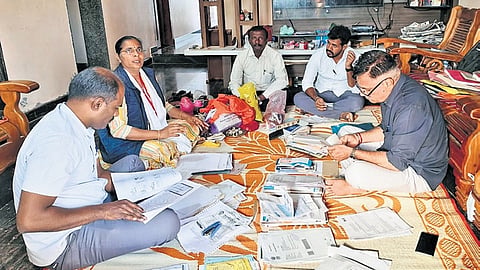 Lokayukta officials examine documents seized from one of the premises they raided on Thursday. 