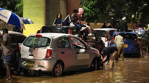 People climb on top of their cars after heavy rains flooded roads in Nairobi, Kenya, on Friday, March 6, 2026. 